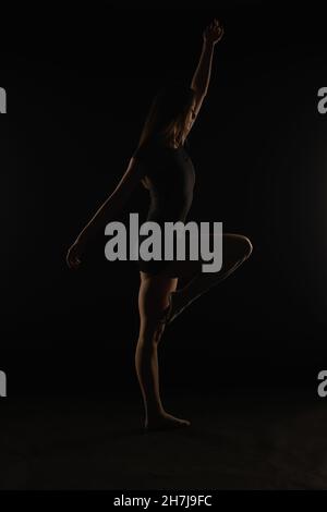 Giovane ballerina in studio è tenuta bella postura mentre si posa, silhouette Foto Stock