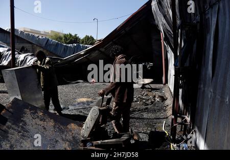 Sanaa, Yemen. 23 novembre 2021. La gente è vista in una fabbrica distrutta in un attacco aereo a Sanaa, Yemen, il 23 novembre 2021. La coalizione a guida Saudita ha bombardato una fabbrica a Sanaa martedì, la milizia Houthi-run al-Masirah TV ha riferito. Credit: Nyooooooooooooooooooooooooooooo Foto Stock