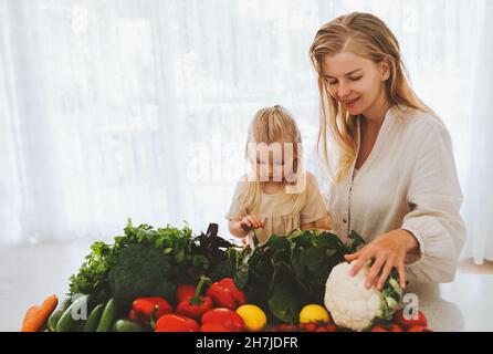 Famiglia vegan madre e figlia bambino che cucinano cibo sano ortaggi biologici nutrizione ingredienti stile di vita sostenibile negozio di alimentari Foto Stock