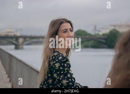 Ragazza turistica sorridente con la sua migliore amica in un viaggio in Europa e Triana Bridge sullo sfondo. Viaggiare durante il virus corona 2021-2022. Foto Stock