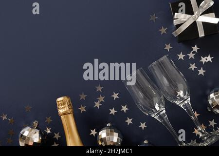 Composizione con champagne di Capodanno, cannucce da bere, palline da discoteca in argento lucido su sfondo blu navy. Vista dall'alto. Biglietto di auguri o invi Foto Stock