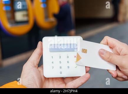 Da sopra di raccolto anonima cliente che effettua il pagamento con carta di credito toccando sul terminale wireless sulla strada Foto Stock