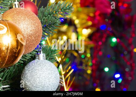 Giocattoli di Natale sull'albero di Natale sullo sfondo colorato di illuminazione. Belle decorazioni di vetro di Natale. Fantastici giocattoli per l'anno nuovo Foto Stock