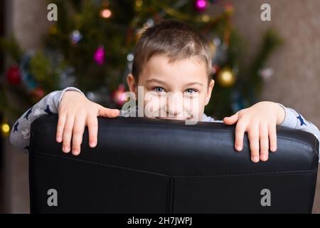 il ragazzo ridendo si sbirciava dietro la sedia. Foto Stock