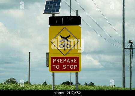 Preparatevi a fermarsi all'incrocio ferroviario con pannello solare per l'alimentazione Foto Stock