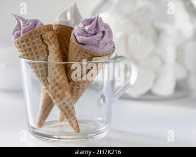 Assortimento di coni per gelato. Fragola e vaniglia in coni waffle. Vista dall'alto su sfondo di marmo bianco. Foto Stock