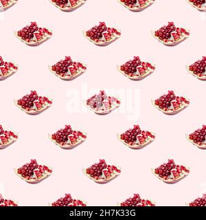 I pezzi in pomergranato rosso brillante ripetono un motivo senza cuciture su sfondo rosa chiaro. Foto Stock
