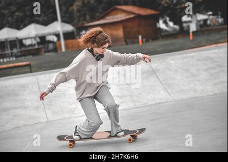 Ragazza su gambe piegate che cavalcano lo skateboard Foto Stock