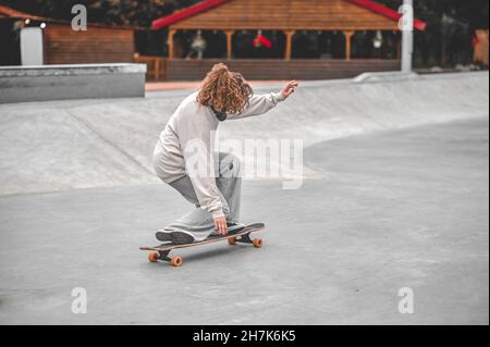 Ragazza su gambe piegate che si equilibrano sullo skateboard Foto Stock