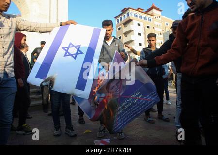 Rafah, Gaza. 23 novembre 2021. I palestinesi bruciano la bandiera di Israele e i manifesti raffiguranti la faccia sbarrata del Segretario di Stato britannico Priti Patel durante un raduno contro la possibile designazione britannica di Hamas come gruppo terroristico, a Rafah nella striscia meridionale di Gaza, martedì 23 novembre 2021. Gli Stati Uniti hanno designato Hamas come gruppo terroristico nel 1995. Foto di Ismael Mohamad/UPI Credit: UPI/Alamy Live News Foto Stock