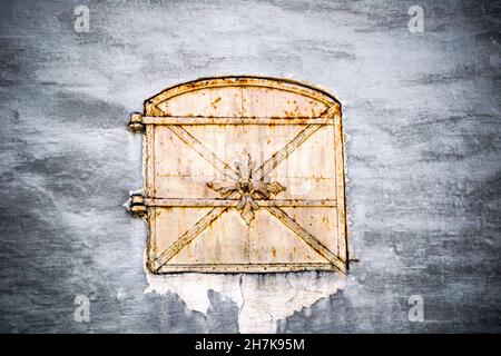 Porta in miniatura in metallo antico per la consegna del carico in una vecchia casa in pietra. Foto Stock