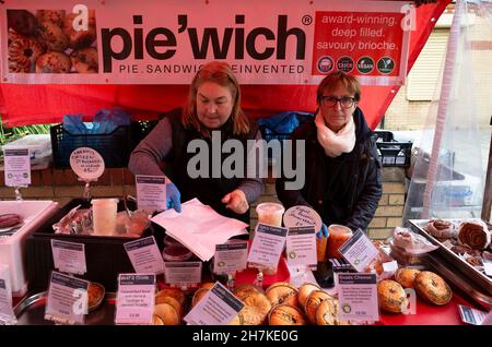 Lady stallholders che serve dalla loro esposizione delle sue torte e torte popolari in stile russo per la vendita al mercato agricolo di Saltburn in estate Foto Stock