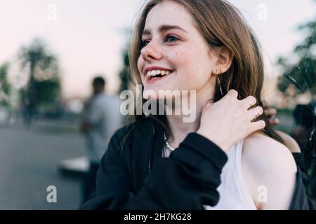 donna felice sorridente mentre si trova vicino a una parete specchiata Foto Stock