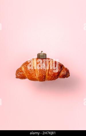 decorazioni natalizie con croissant su sfondo rosa. Concetto di Capodanno minimalista. Primo piano Foto Stock
