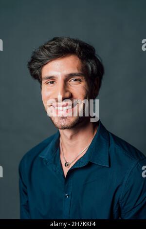 Giovane uomo sorridente su sfondo grigio Foto Stock