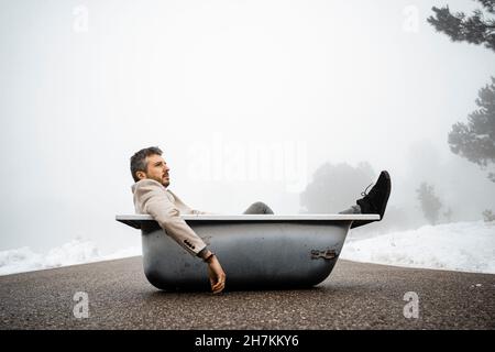 Uomo che contempla mentre si rilassa nella vasca da bagno su strada Foto Stock