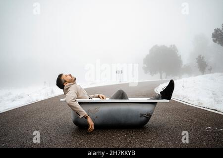 Uomo stanco che si rilassa nella vasca da bagno sulla strada Foto Stock