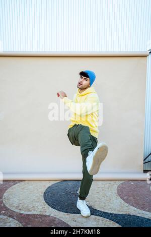 Giovane interprete maschile che balla mentre si bilancia su una gamba sullo sfondo Foto Stock