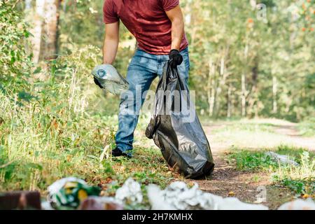 Uomo ambientalista adulto medio che mette bottiglia di plastica in sacco per rifiuti Foto Stock