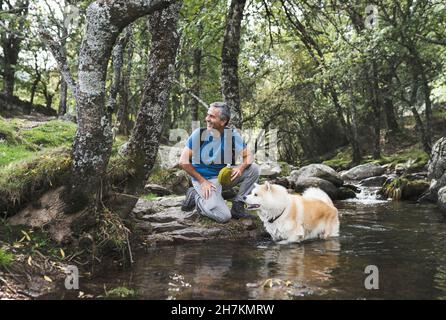 Uomo che guarda il cane che nuota in acqua Foto Stock