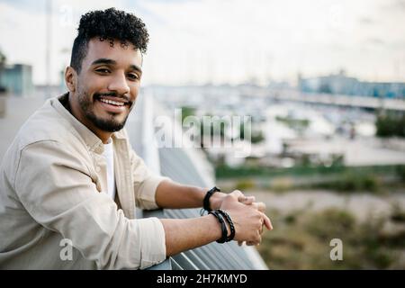 Sorridente uomo barbuto in piedi sulla terrazza dell'edificio Foto Stock