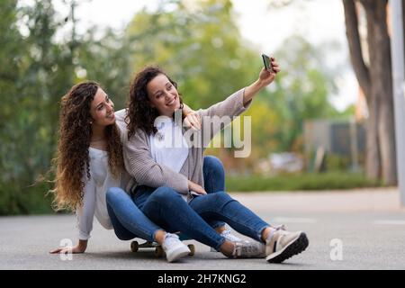 Allegre giovani amiche che si divertono mentre si skateboard nel parco Foto Stock