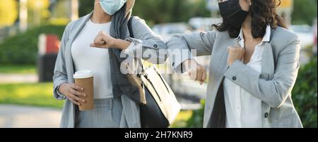 Donna d'affari che fa il gomito a bussare a collega in parco durante COVID-19 Foto Stock