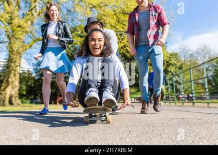 Giovane donna che gioca con gli amici nel parco Foto Stock
