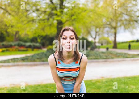 Donna giocosa che attacca la lingua al parco pubblico Foto Stock