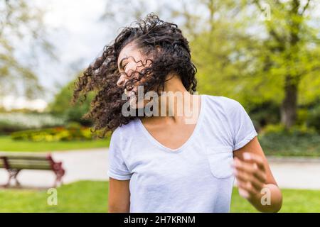 Donna spensierata che lancia i capelli al parco Foto Stock