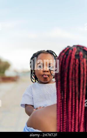 Donna intrecciata che porta figlia Foto Stock