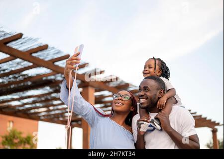 Famiglia sorridente che prende selfie attraverso il telefono cellulare Foto Stock