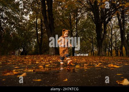 Ragazzo con impermeabile marrone che cammina nel parco Foto Stock