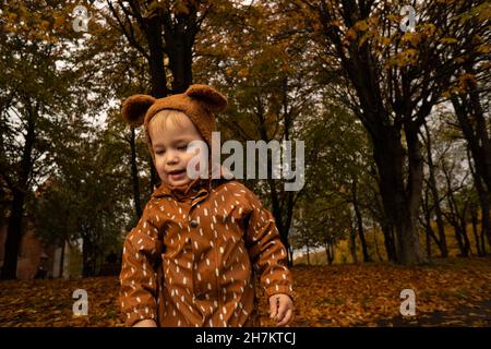 Bimbo con cappello marrone e impermeabile al parco autunnale Foto Stock