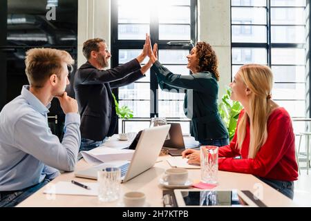 I colleghi che si acclamano durante la riunione in ufficio Foto Stock