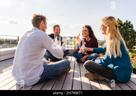 Colleghi felici che tostano bevande sul tetto Foto Stock