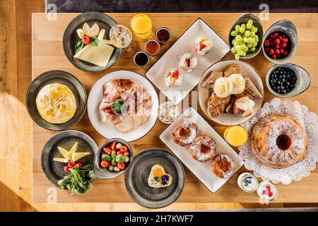 Studio shot di tavolo per la colazione riempito con vari dessert, frutta e verdura Foto Stock