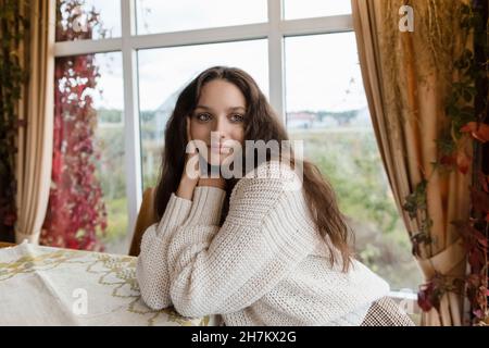 Giovane donna che indossa un pullover appoggiato sul tavolo Foto Stock