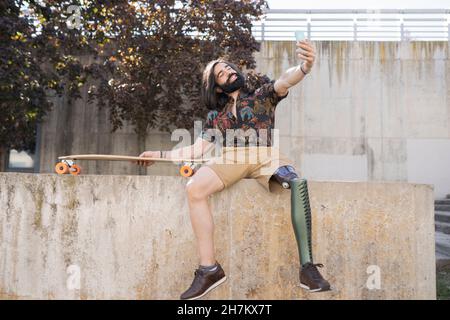 Uomo disabile sorridente con un notebook che si sposta in basso sui gradini Foto Stock