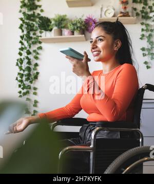 Donna con disabilità sorridente che parla sul cellulare a casa Foto Stock