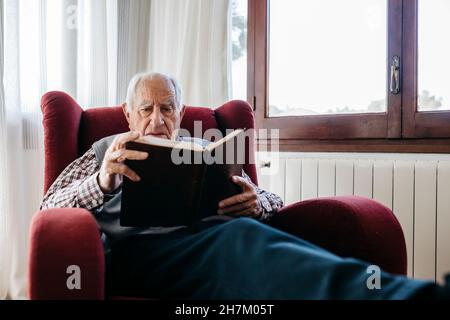 Uomo che copre il viso con orologio da parete a casa Foto Stock