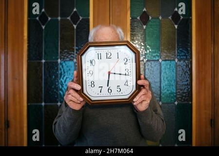 Uomo che tiene l'orologio da parete a casa Foto Stock