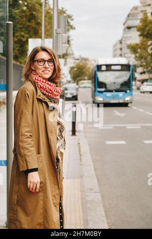 Donna sorridente alla fermata dell'autobus su strada Foto Stock