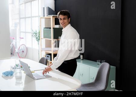 Uomo d'affari sicuro con un notebook alla scrivania in ufficio Foto Stock
