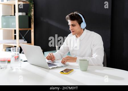 Uomo d'affari sicuro con la tazza di caffè in piedi davanti alla parete nera Foto Stock