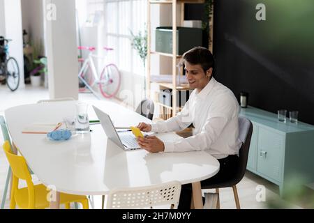 Uomo di lavoro sorridente che usa il laptop alla scrivania in ufficio Foto Stock