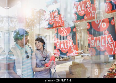 Coppia che fa shopping nel negozio di scarpe visto attraverso il vetro Foto Stock