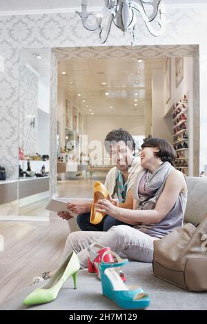 Coppia allegra che guarda i sandali mentre fai shopping nel negozio di scarpe Foto Stock