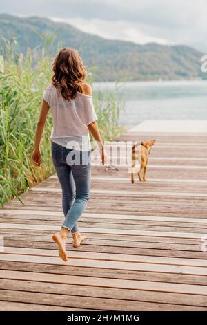 Donna e cane che camminano sul molo Foto Stock