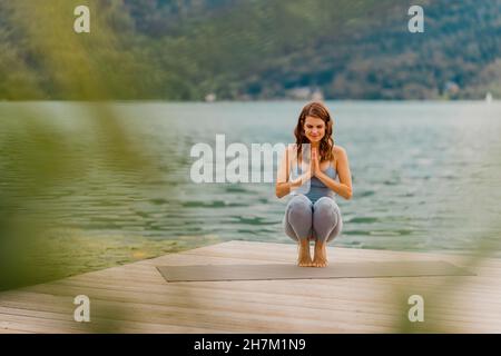 Donna meditating mentre fa yoga sul jetty Foto Stock